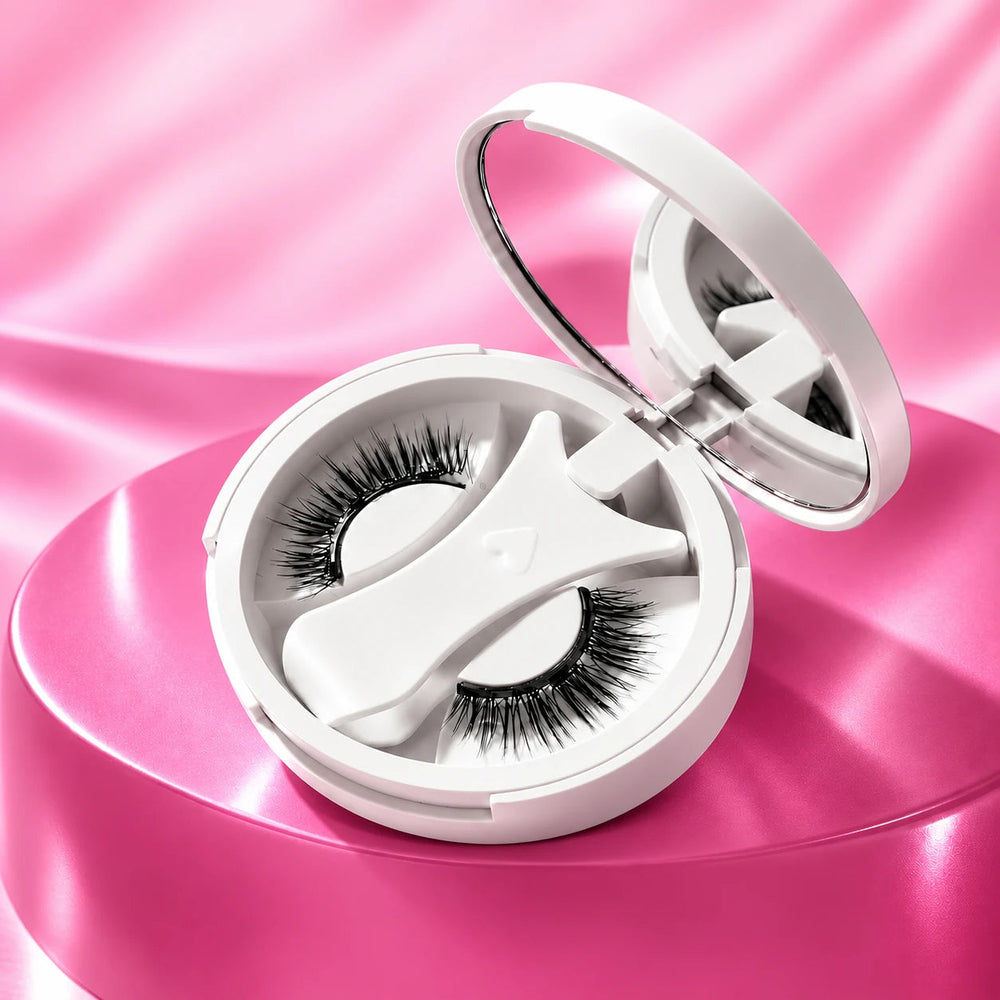 Magnetic lash kit with mirrored compact, shaped applicator and lashes on pink.